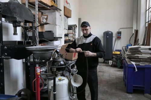 Operario revisando una linea de aire comprimido en un taller, con el deposito del compresor al fondo