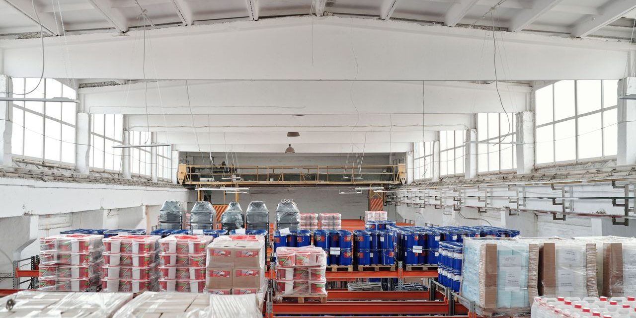 Nave industrial preparada para la parada de agosto Interior de un almacen industrial ordenado con estanterias, palets y bidones antes del cierre por vacaciones
