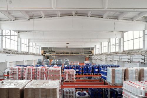 Interior de un almacen industrial ordenado con estanterias, palets y bidones antes del cierre por vacaciones