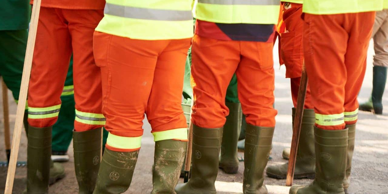 Dotacion de vestuario laboral y proteccion para un trabajador nuevo Grupo de operarios con ropa de alta visibilidad y botas de seguridad