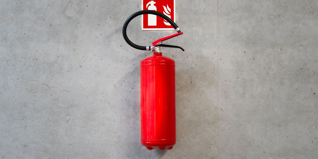 Extintor rojo colgado en la pared bajo su senal de senalizacion de equipo contra incendios