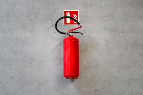 Extintor rojo colgado en la pared bajo su senal de senalizacion de equipo contra incendios
