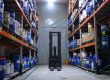 Pasillo de un almacen industrial con estanterias cargadas y una carretilla elevadora al fondo