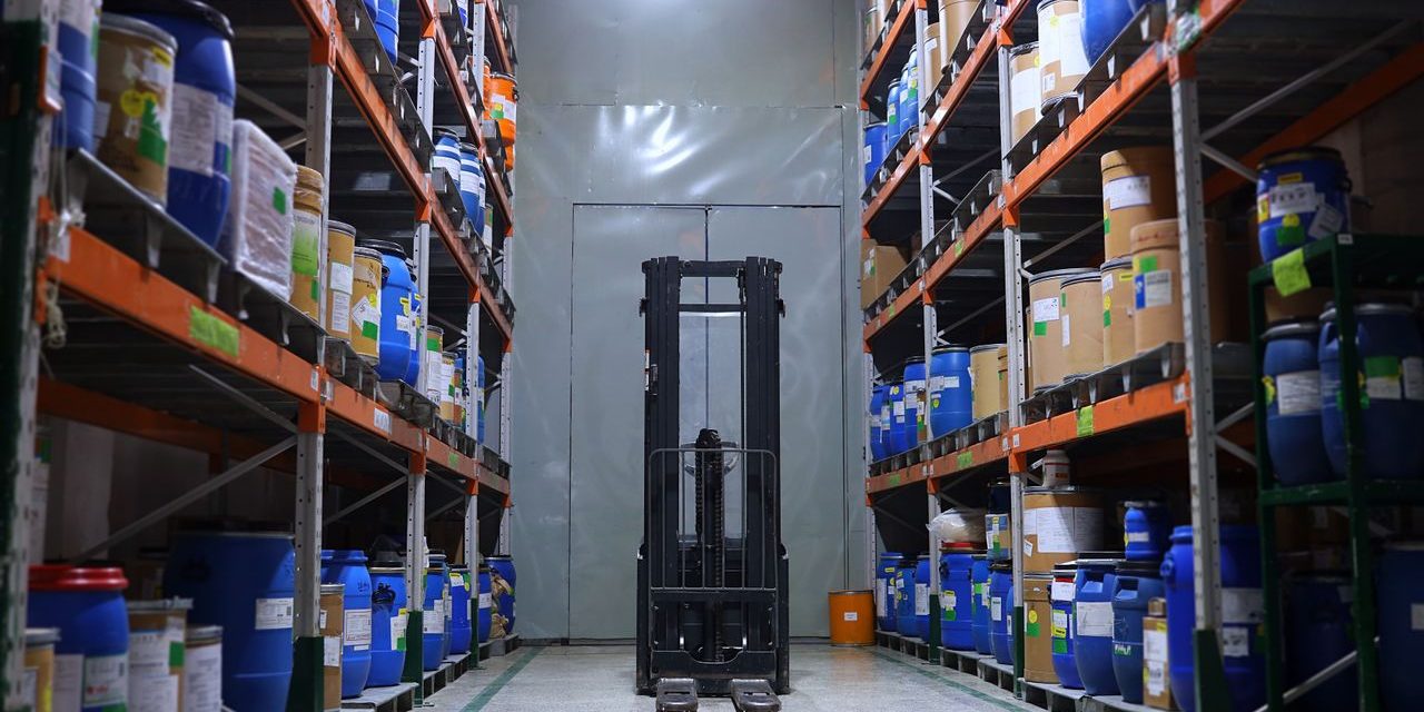 Carretilla elevadora en un almacen industrial Pasillo de un almacen industrial con estanterias cargadas y una carretilla elevadora al fondo