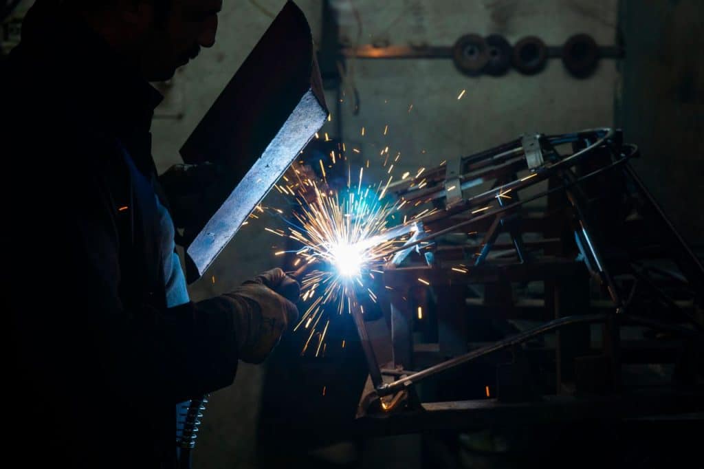 Soldador con pantalla de proteccion trabajando entre chispas en un taller