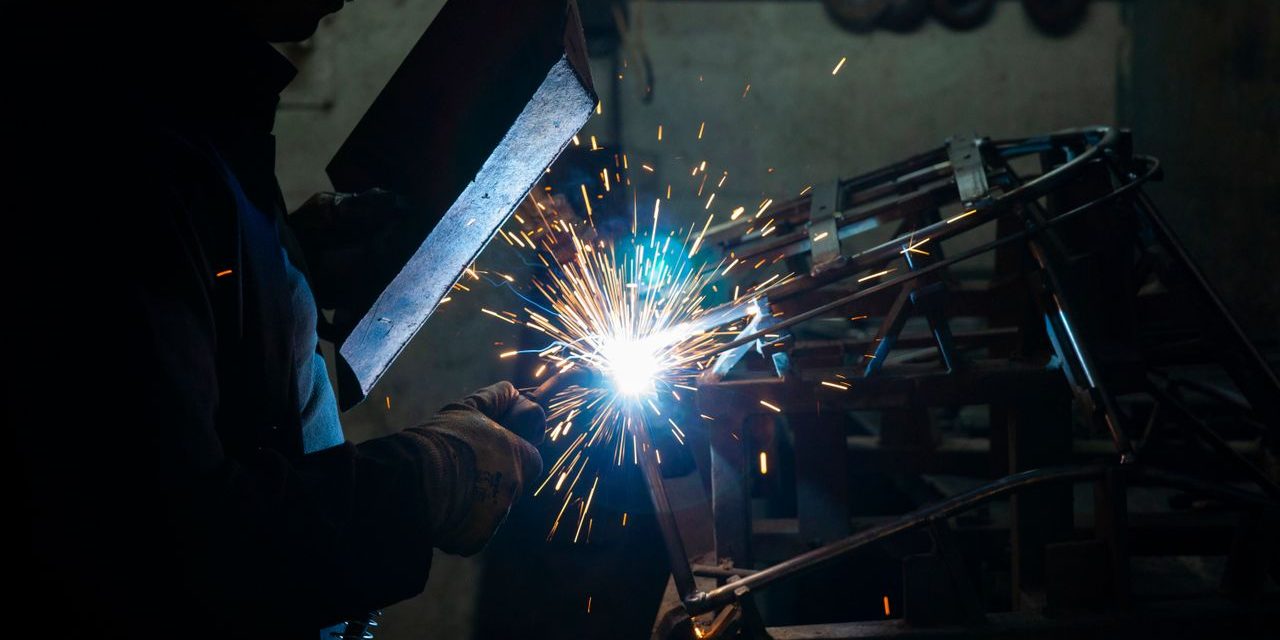 Soldador con pantalla de proteccion trabajando entre chispas en un taller